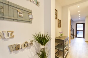 Un área de recepción con un letrero que dice 'Welcome', una planta en maceta y un escritorio con un florero.