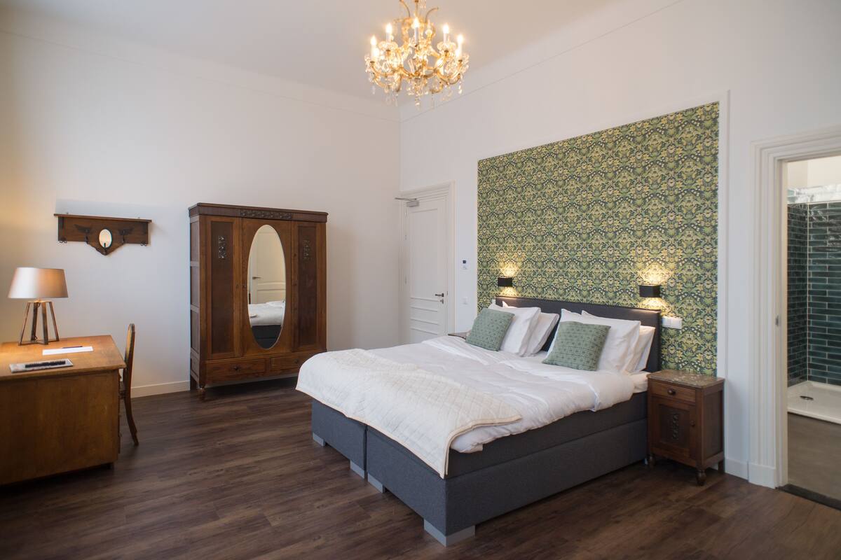 Une chambre à coucher avec un lit, une armoire en bois, un bureau et un lustre.