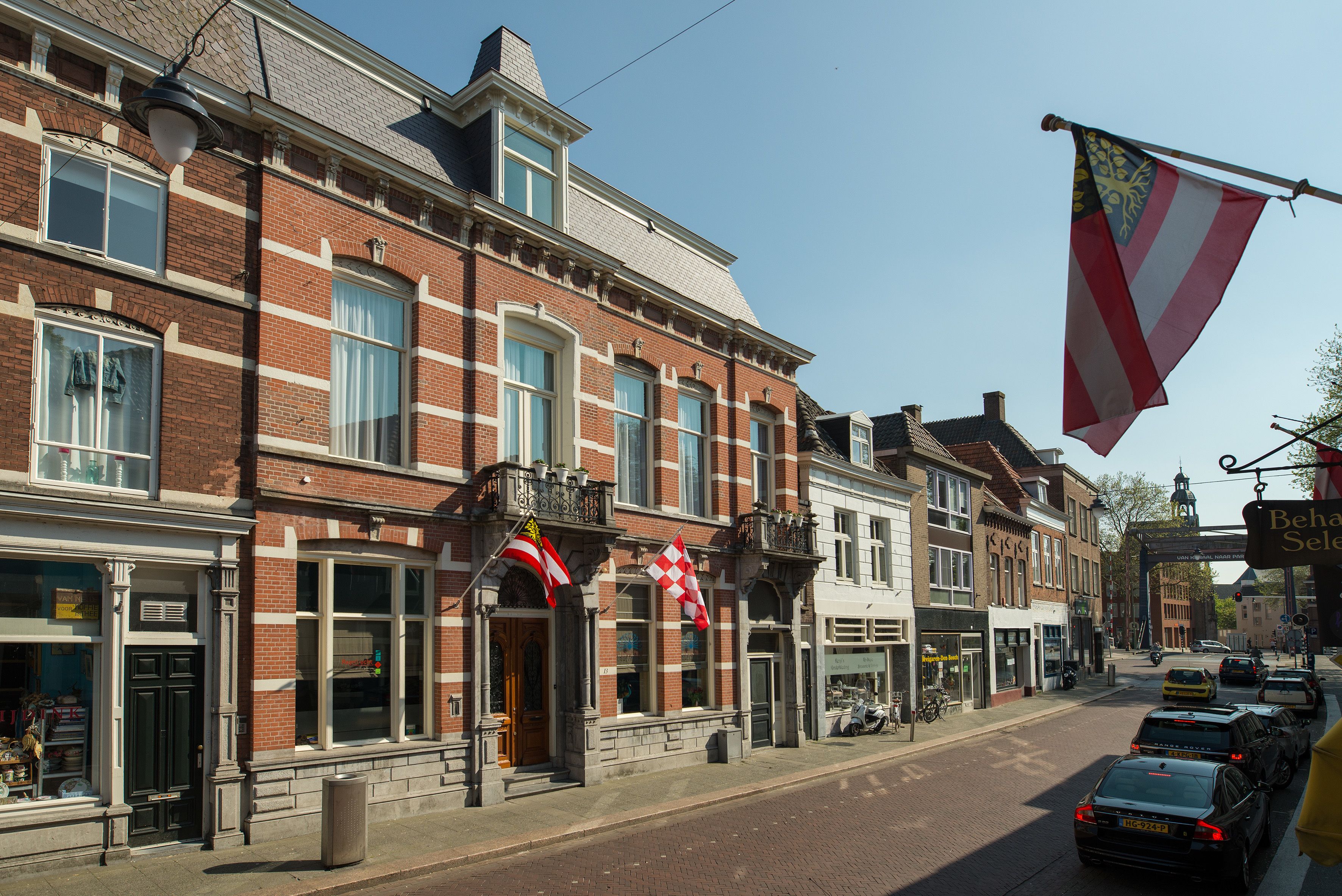 Een straatbeeld van een historisch pand met diverse winkels op de begane grond.