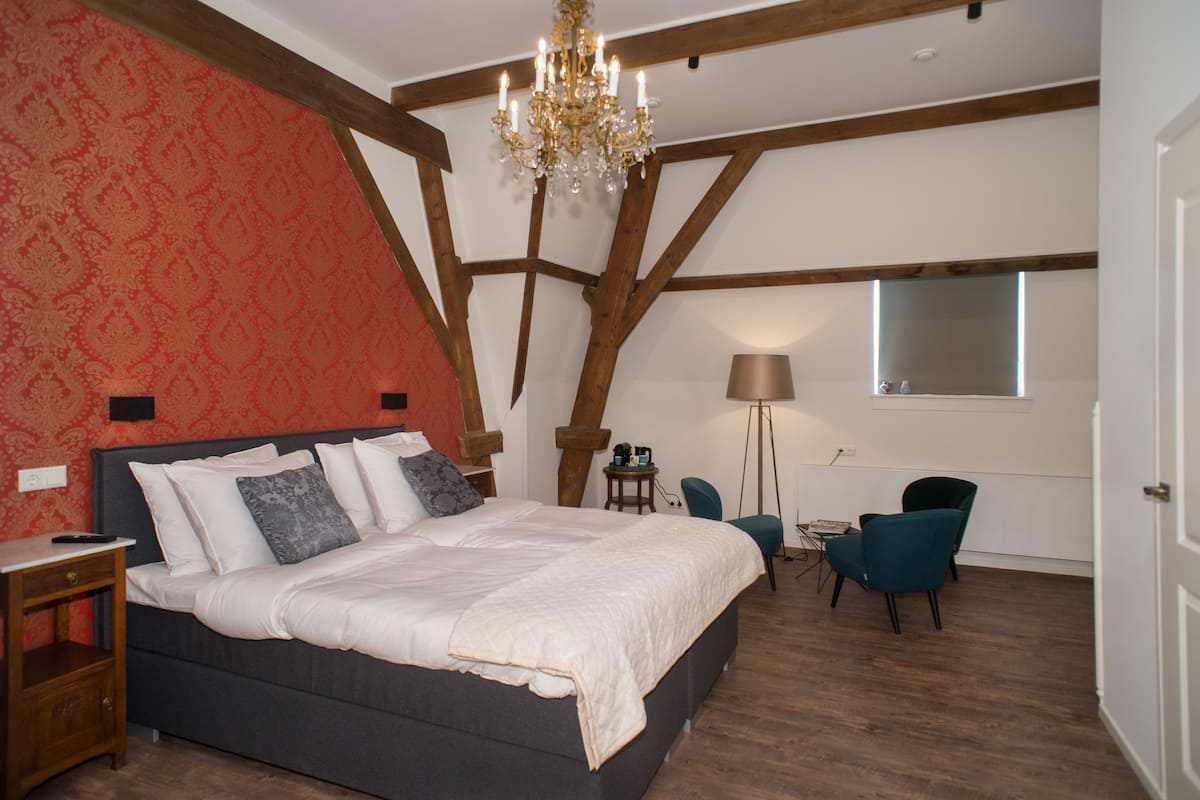 Une chambre à coucher avec un grand lit, un lustre, un bureau et une chaise.