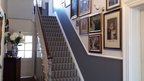 A grand staircase with a chandelier, framed pictures, and a vase with flowers. - Canterbury Lodge (Canterbury)