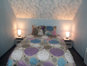 Une chambre à coucher avec une couvre-lit à motifs, deux lampes de chevet et un plafond décoratif.