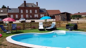 Ein Garten mit Schwimmbad, Liegestühlen und Holzzaun.