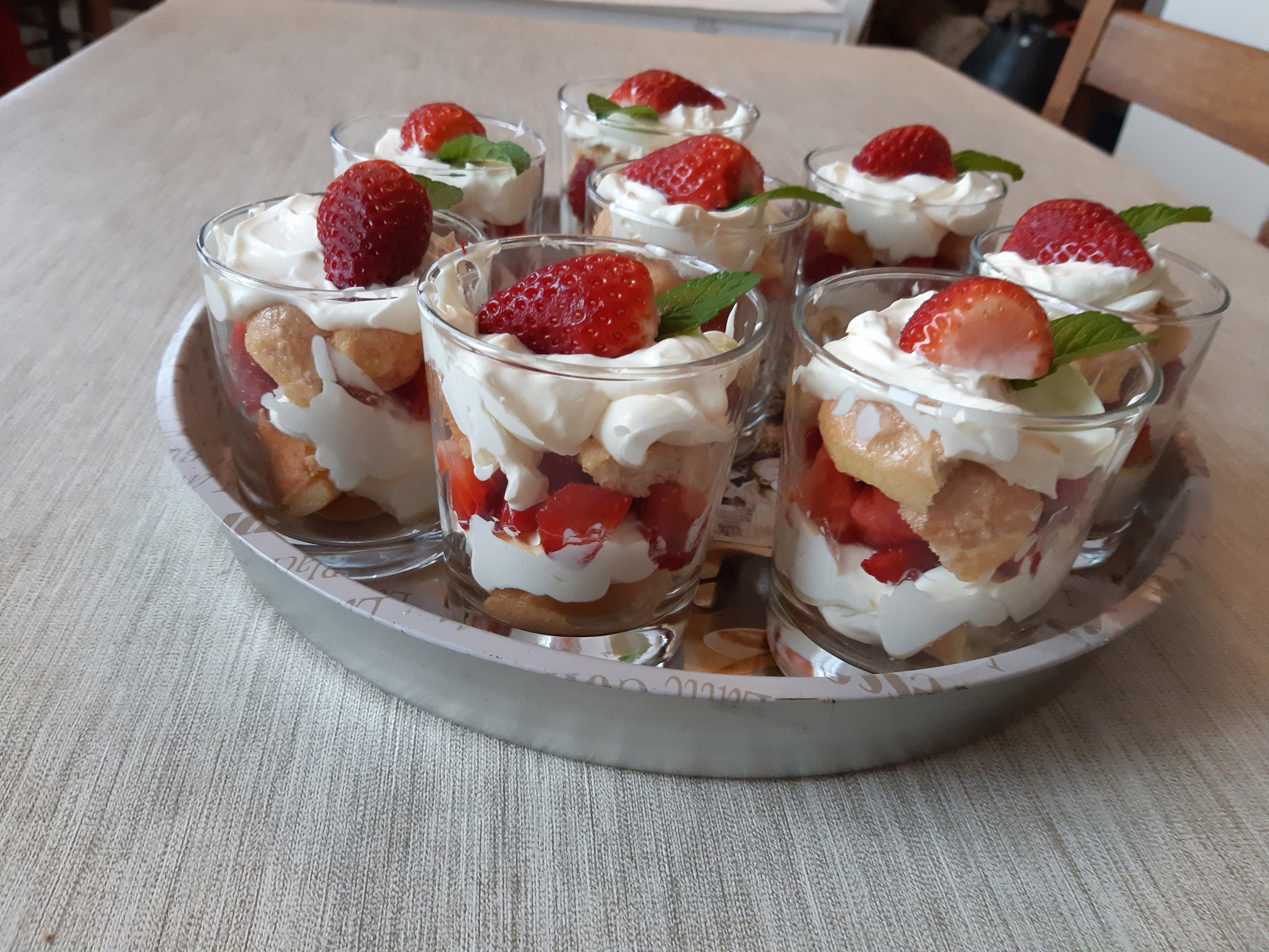 Una bandeja con copas de postre, fresas y hojas de menta.
