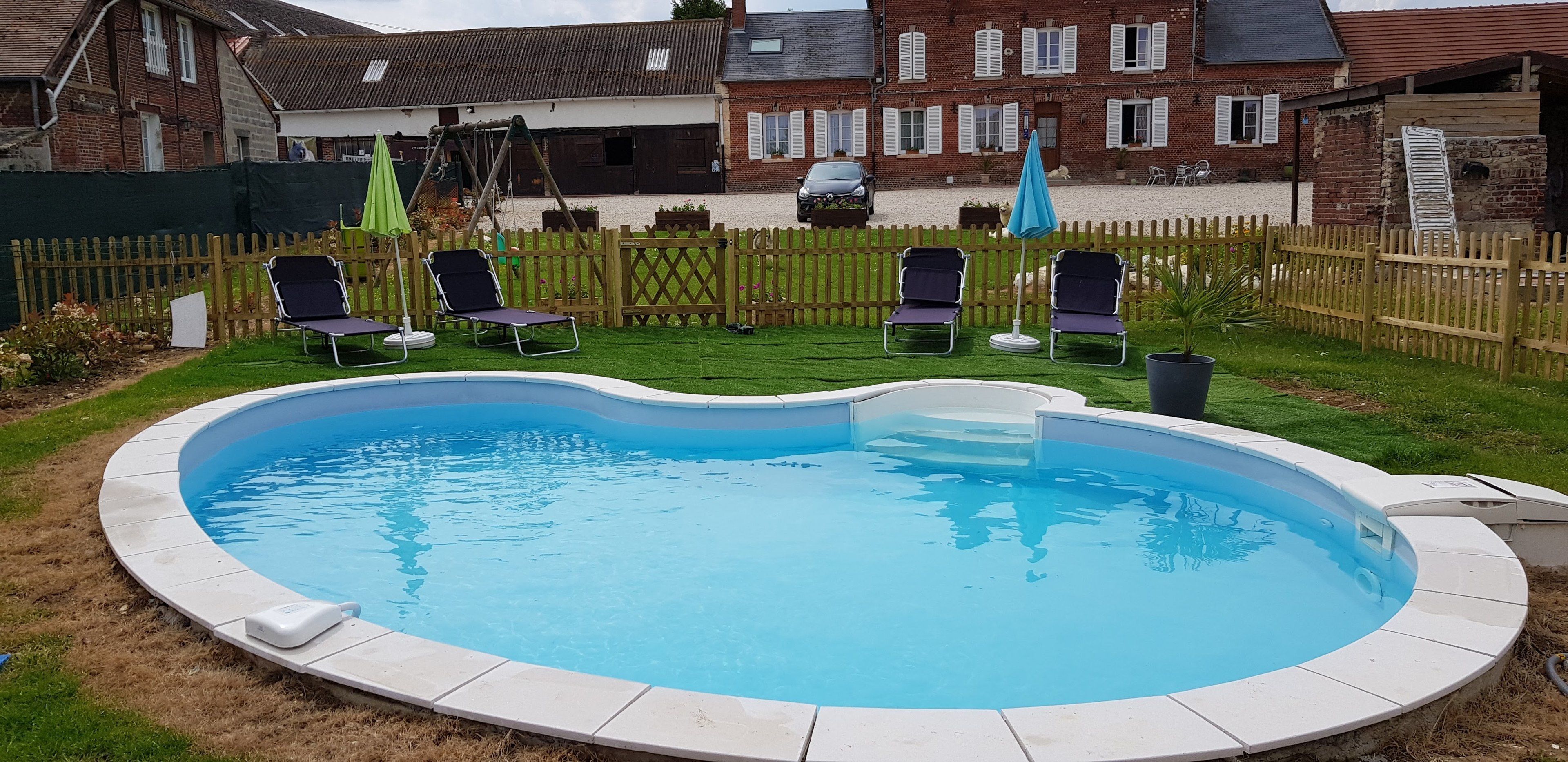 Una piscina circular con borde blanco, rodeada por una valla de madera.