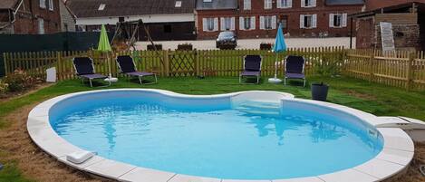 Una piscina circular con borde blanco, rodeada por una valla de madera.