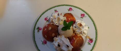 Un plato de postre con compota de frutas, nueces y crema batida sobre un plato estampado con motivos florales.
