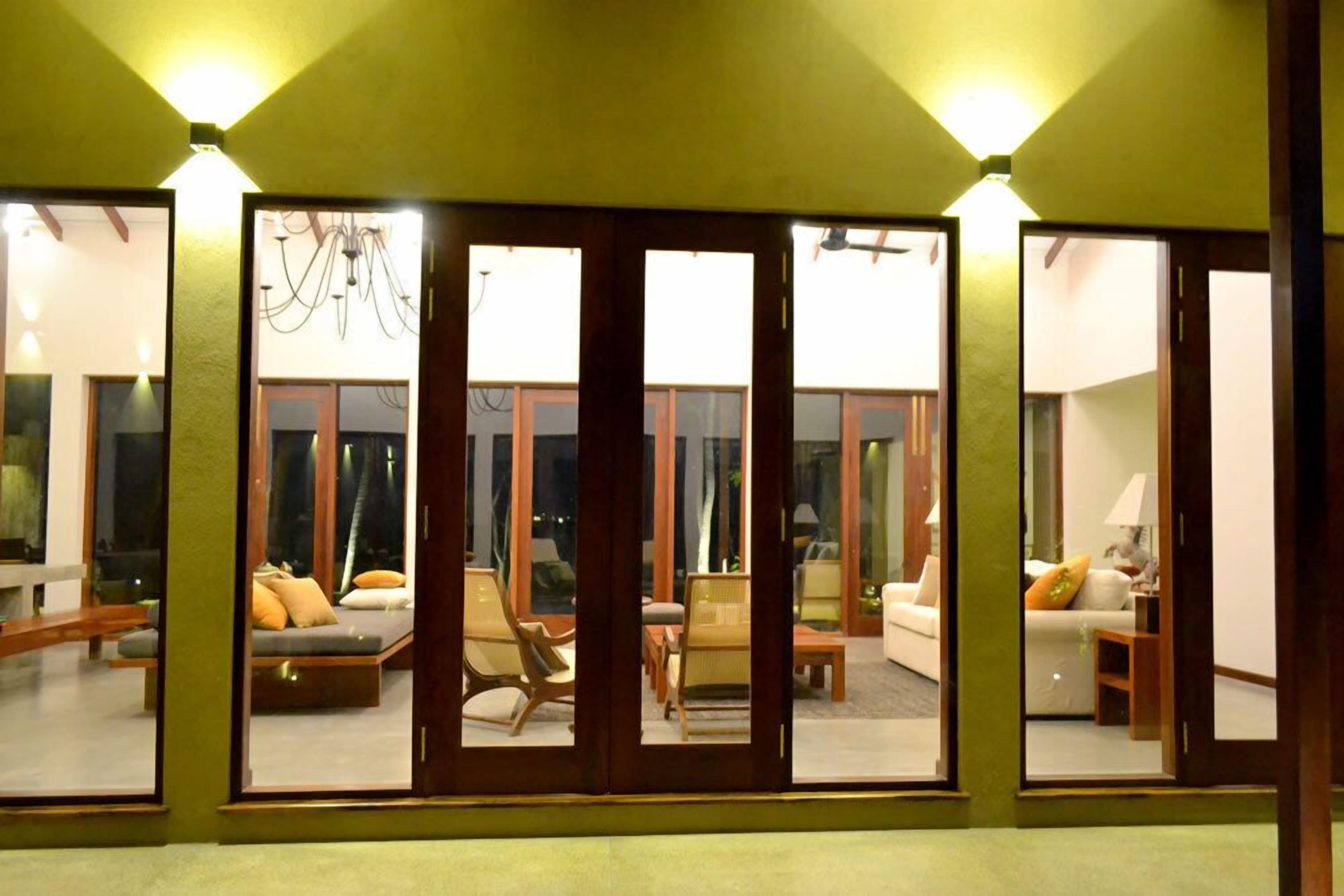 A modern interior with large sliding glass doors leading to a balcony, wooden furniture, and a chandelier.