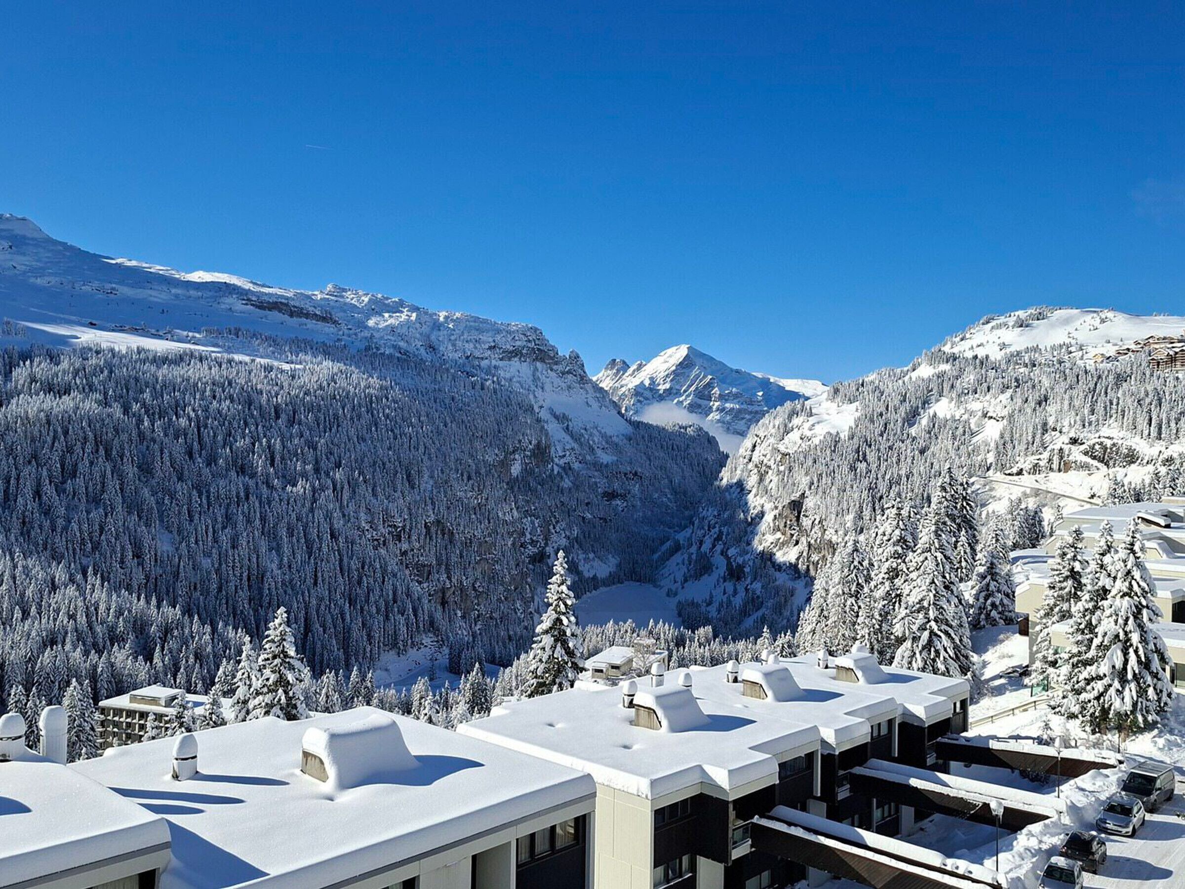 A hotel with multiple buildings, snow-covered roofs, and a mountainous backdrop.