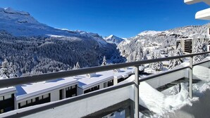 Un paysage montagneux enneigé, avec des bâtiments au premier plan.