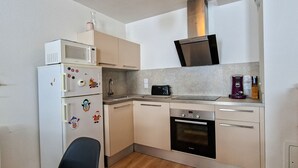 Eine kompakte Küche mit Mikrowelle, Toaster, Backofen und Kaffeemaschine.