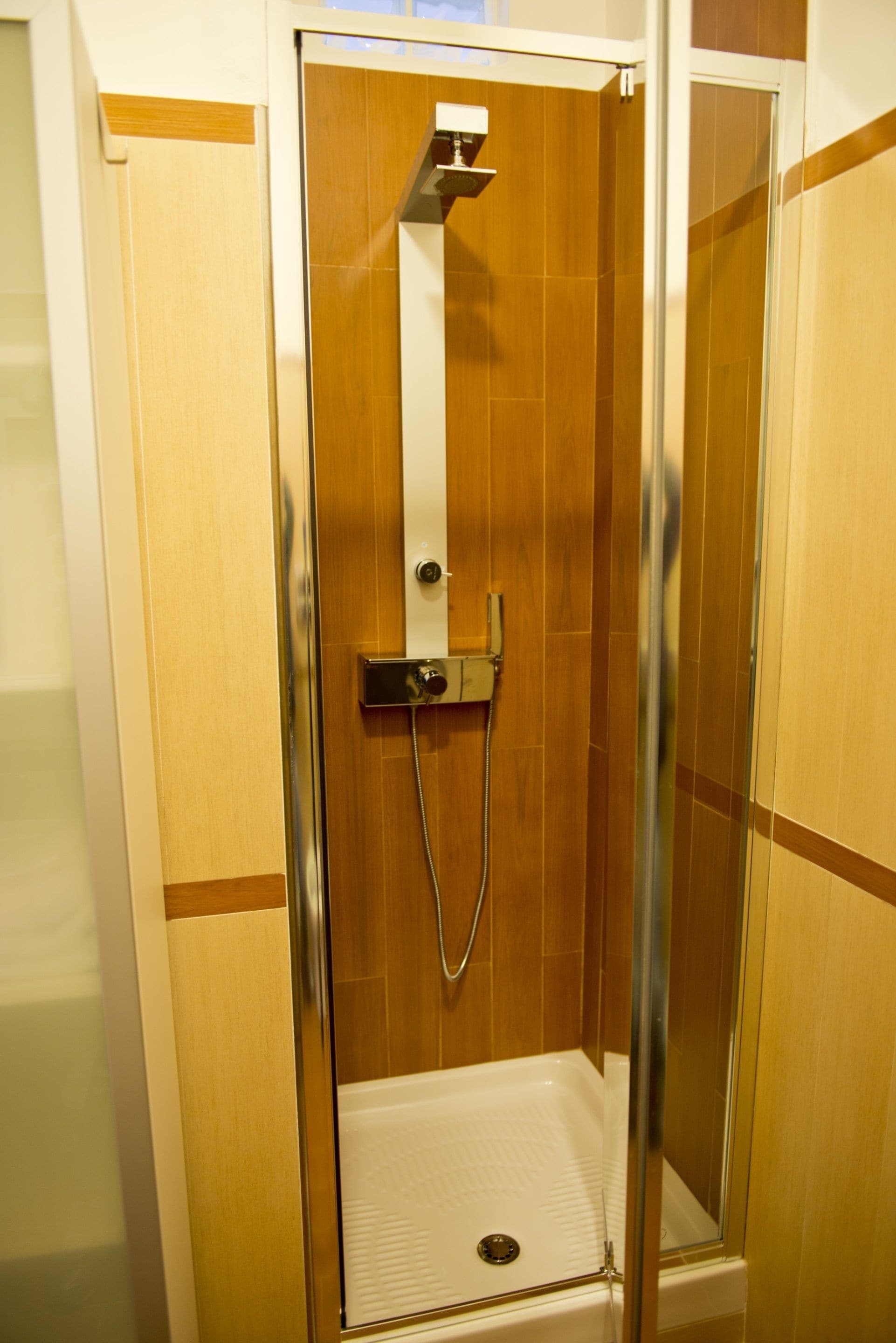 A glass-enclosed shower stall with a showerhead and control panel.