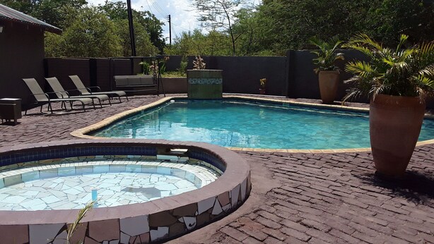 A swimming pool with lounge chairs and a hot tub area. - Sweet Holiday Homes (Victoria Falls)