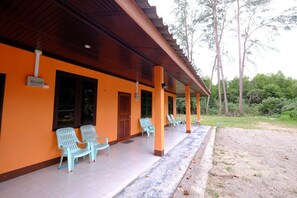 A building with an orange exterior, a covered porch with plastic chairs, and a wooden ceiling. - Ladawan Resort (Sikao)