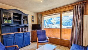 Une pièce comprenant un meuble bleu, une télévision, un canapé, une chaise et une table.