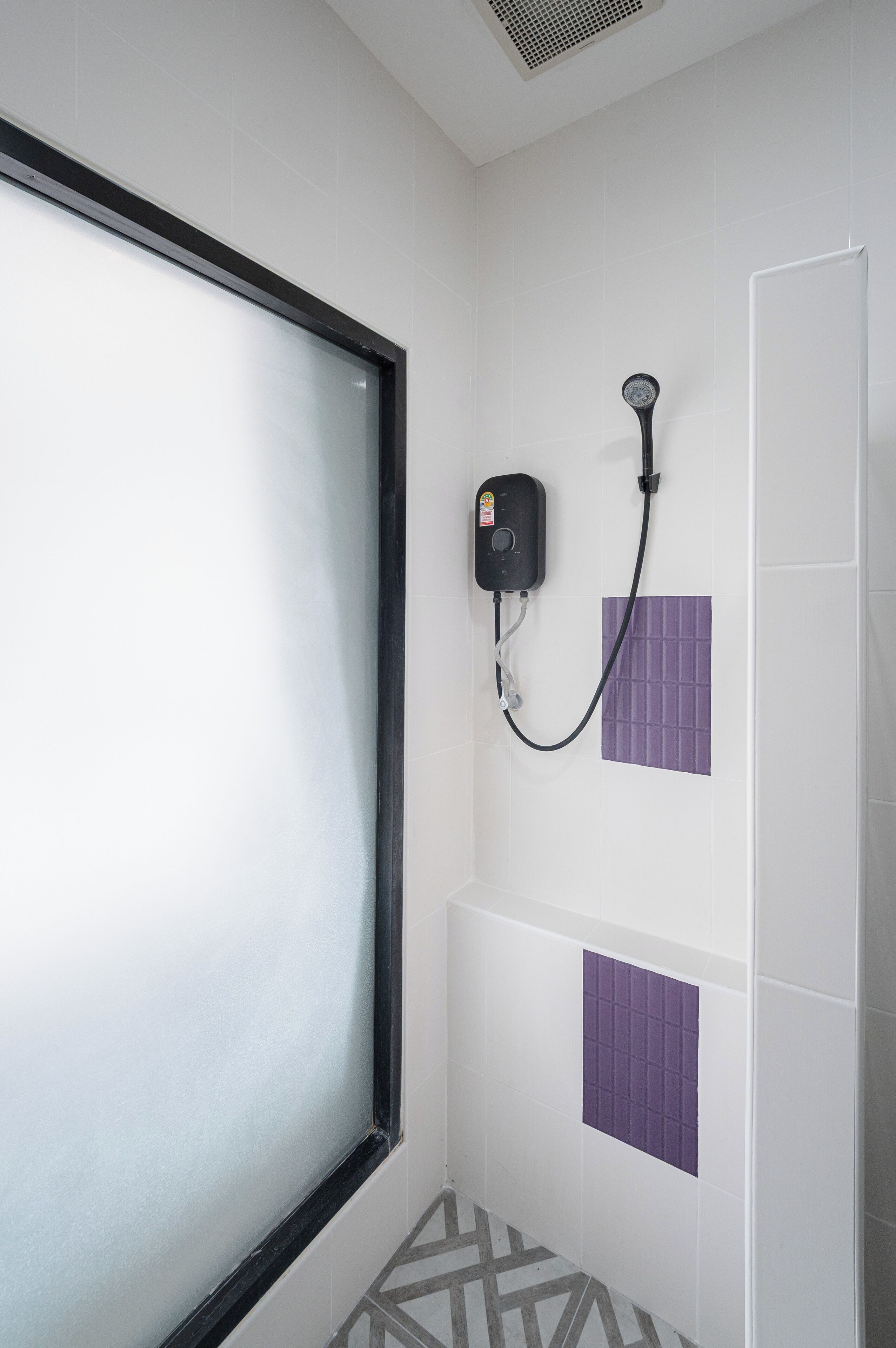 A bathroom with a shower, a window, and a wall-mounted heater.