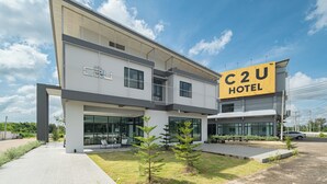 A modern hotel with a prominent 'C2U HOTEL' sign, large windows, and a well-maintained lawn.