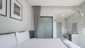 A hotel room with a large bed, a bedside table with towels, a wall-mounted fan, and framed artwork.