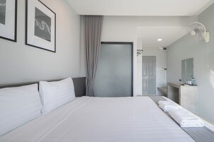 Habitación de hotel con una cama grande, una mesita de noche con toallas, un ventilador de pared y obras de arte enmarcadas.