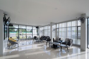 Un salón amplio y moderno con ventanas grandes, asientos cómodos y un piso limpio y pulido.