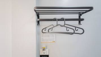 Ein an der Wand befestigtes Metallregal mit zwei Haken, einer kleinen Beschilderung und einem Bedienfeld darunter.