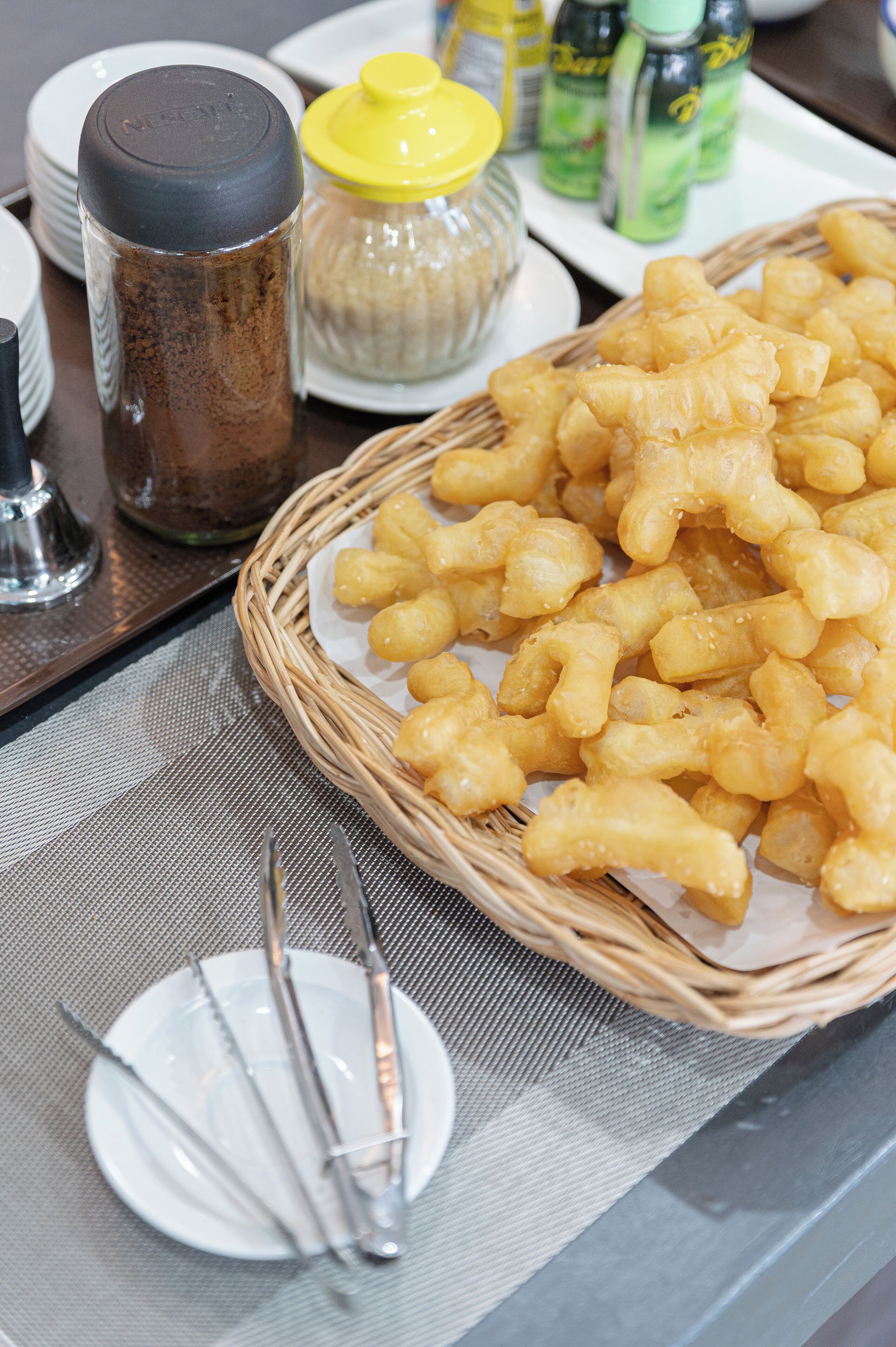 A table with a basket of fried snacks, a salt shaker, a pepper shaker, and condiments.