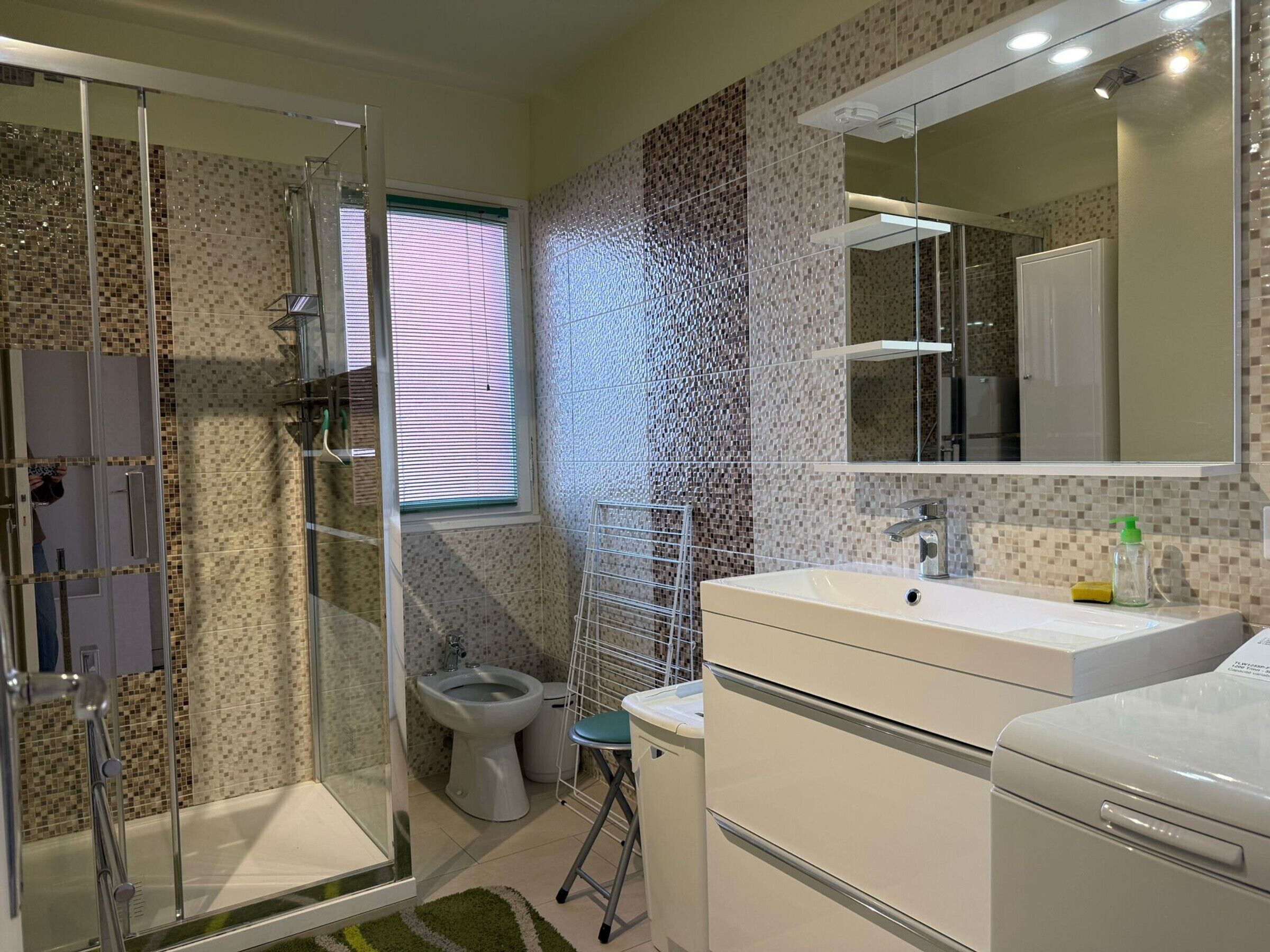 Une salle de bain moderne avec une douche à parois de verre, des toilettes et un lavabo avec un miroir au-dessus.