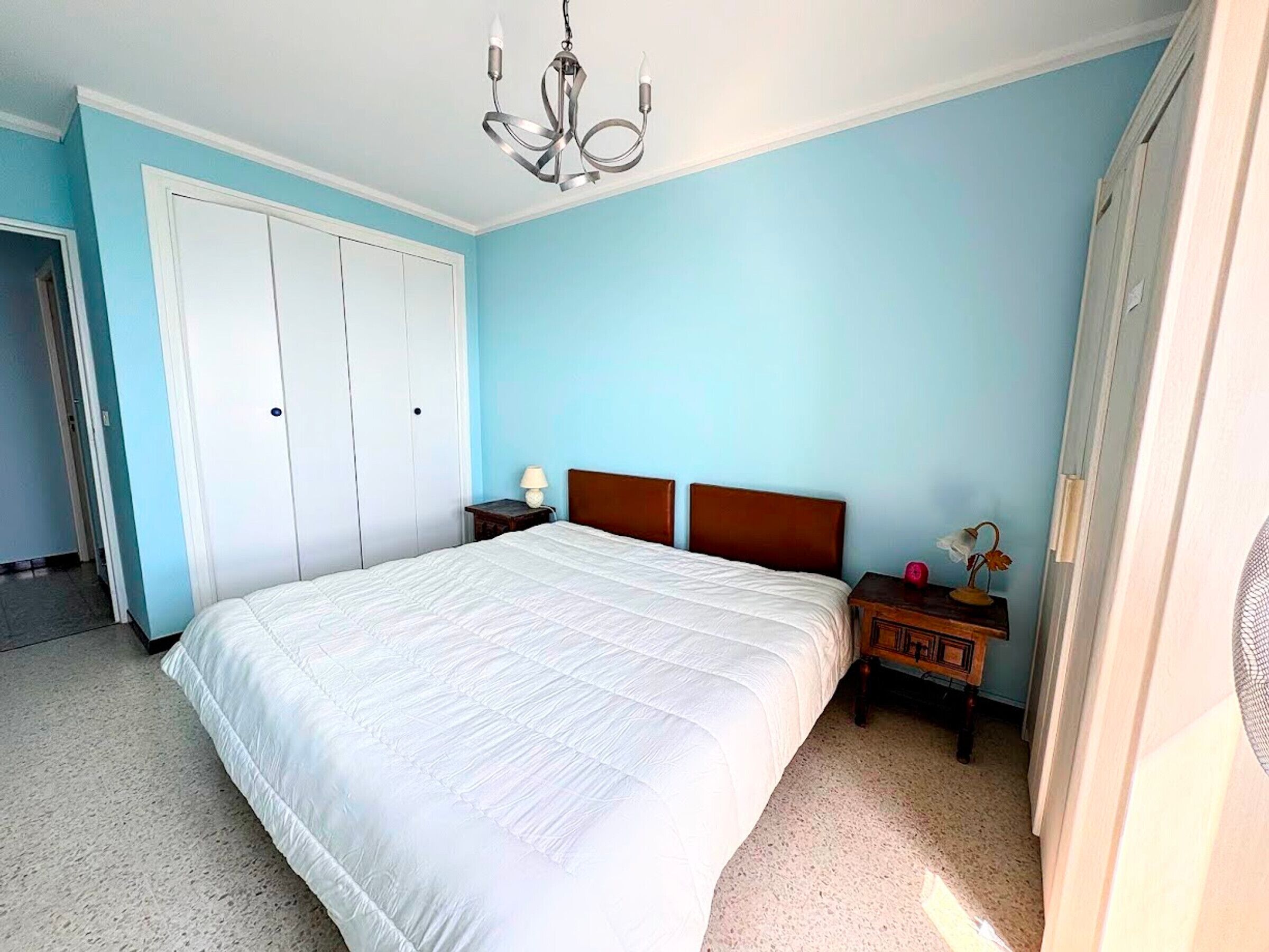 Una camera da letto con un letto grande, una testiera in legno, un comodino con una lampada e un armadio.