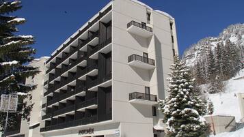 Un immeuble à plusieurs étages, doté d’un design moderne, avec une série de balcons et une façade en pierre.