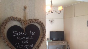 A room with a heart-shaped chalkboard on the wall, a television on a stand, and a small table with items on it. - Charming in the center of the village of Maussane Les Alpilles with patio (Maussane-les-Alpilles)