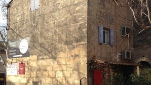 A stone building with a red door, a sign for a bakery, and a sign for a restaurant. - Charming in the center of the village of Maussane Les Alpilles with patio (Maussane-les-Alpilles)