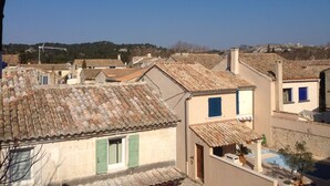 A residential area with terracotta-tiled roofs, a clear sky, and a distant hill. - Charming in the center of the village of Maussane Les Alpilles with patio (Maussane-les-Alpilles)