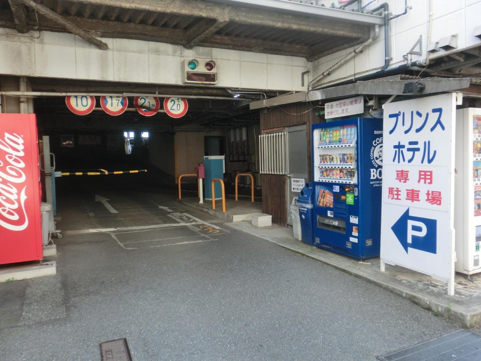 A parking garage entrance with Coca-Cola vending machines and a sign indicating a parking area.