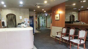 A reception area with a counter, chairs, and a mirror. - Prince Hotel Shimonoseki (Shimonoseki)