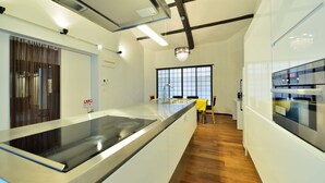 A modern kitchen with a central island, wooden flooring, and a large window providing natural light. - Takeya Kitano Honkan (Kyoto)