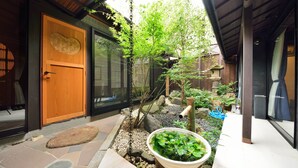 A traditional Japanese-style entrance with a wooden door, a stone pathway, and a small garden with a pond and rocks. - Takeya Kitano Honkan (Kyoto)