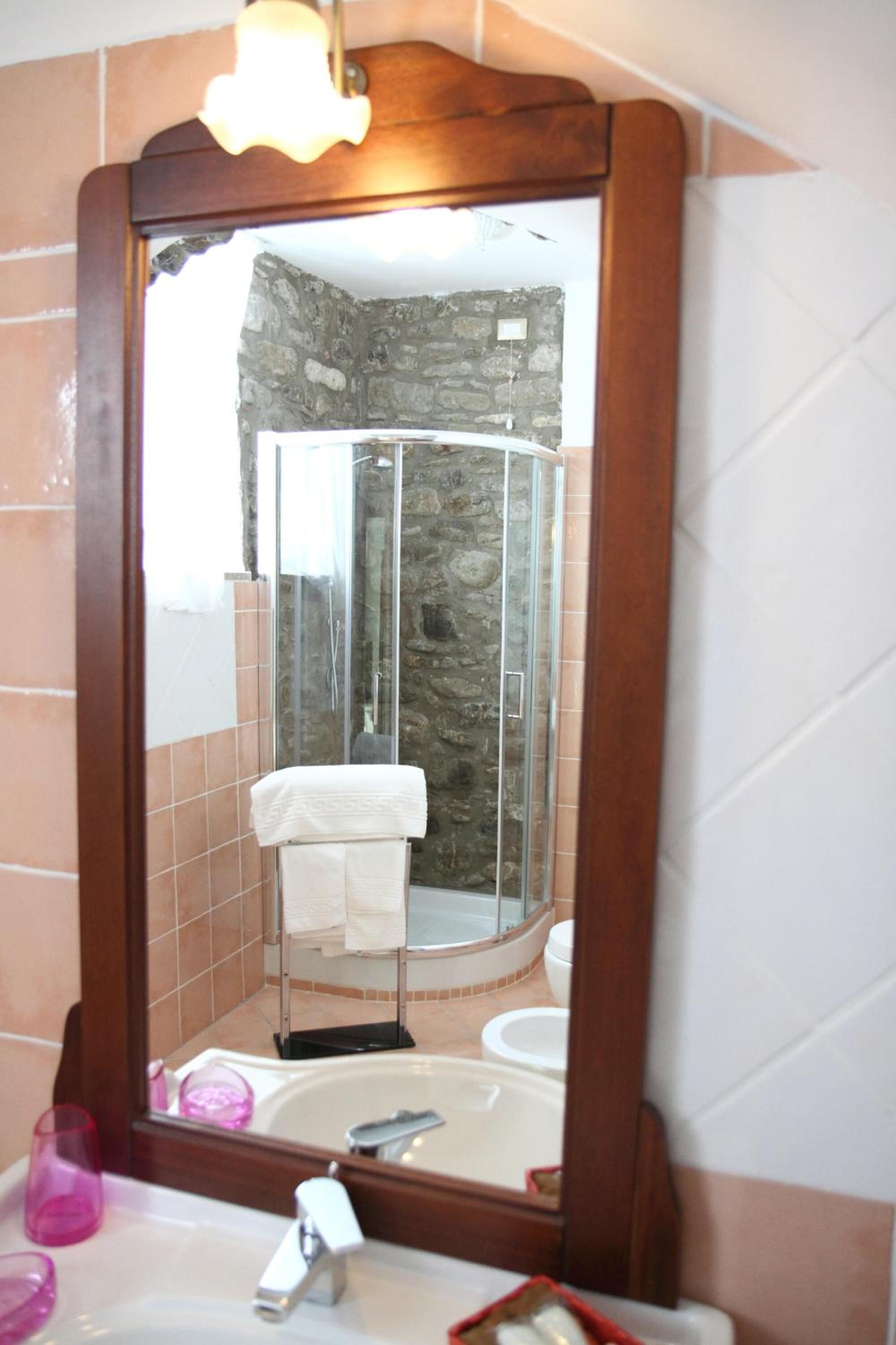 A bathroom with a large mirror, a shower enclosure, and a sink with a towel rack.