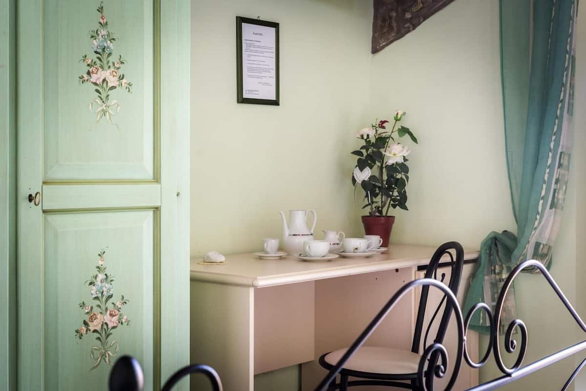 Ein Zimmer mit grüner Tür, einem Schreibtisch mit Teeservice, einer Topfpflanze und einem Stuhl.