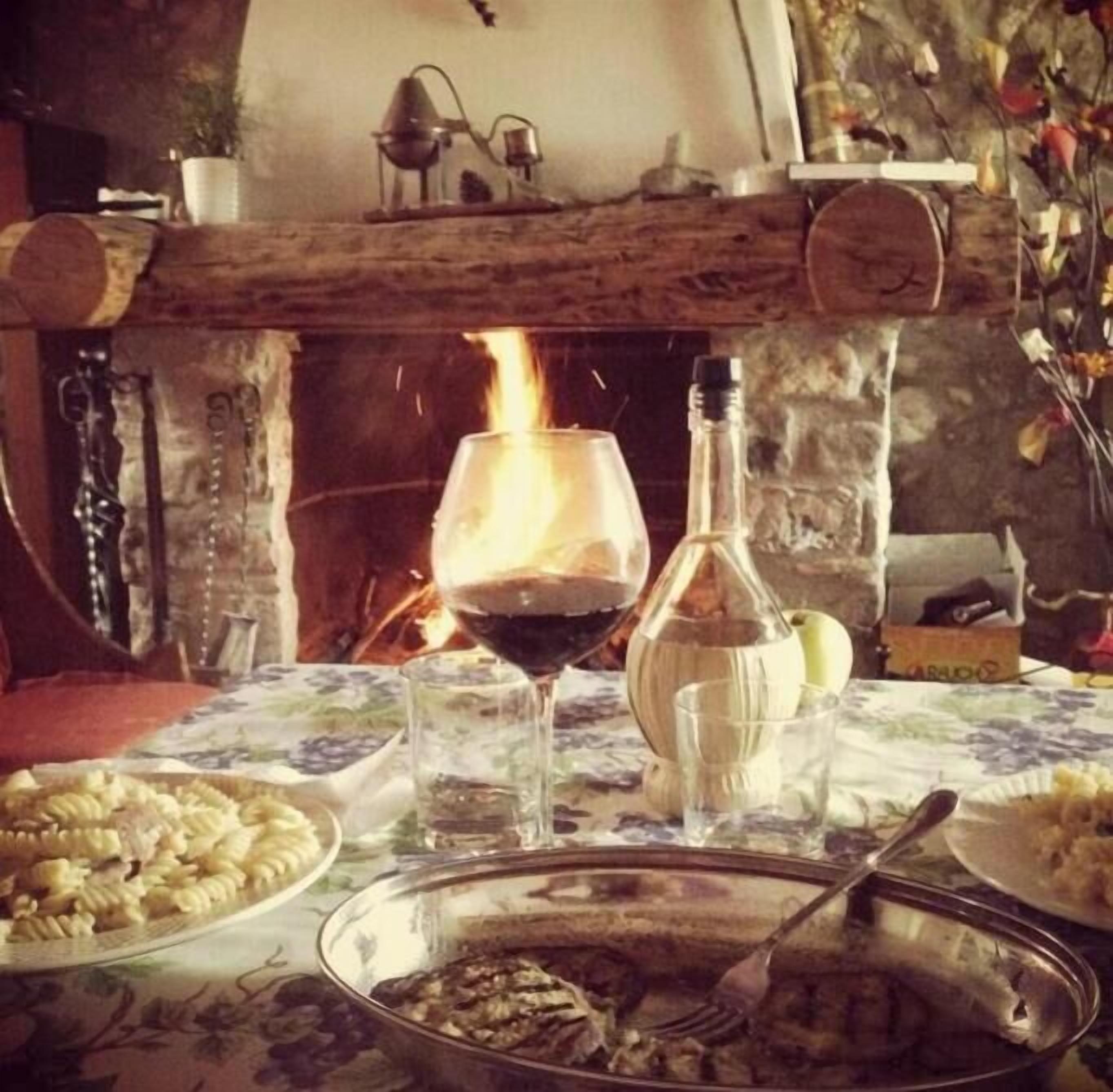 A dining table with a plate of pasta, a bottle of wine, and glasses.