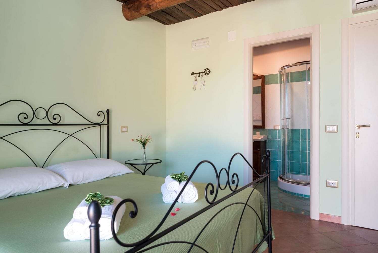 Un dormitorio con cama, una mesita de noche con una planta y un baño con ducha.