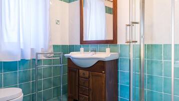 A bathroom with a sink, mirror, and shower.