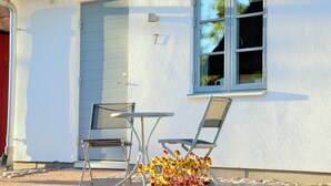 A house with a white exterior, a blue door, and a window with a number '7' on the wall. - KUSKAHUSEN VANDRARHEM (Brosarp)