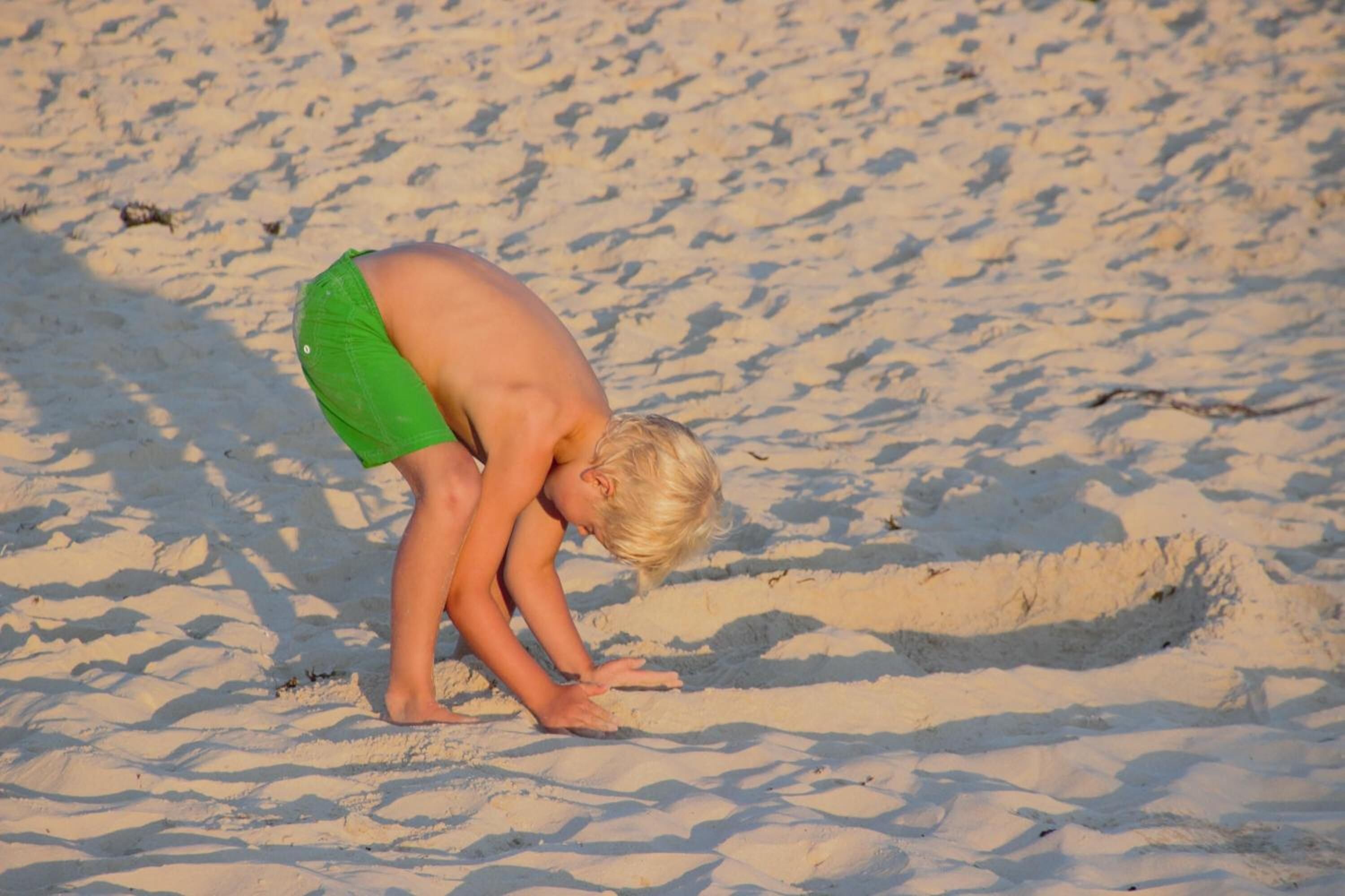 Ett barn som leker i sanden på en strand.