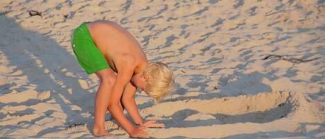 Ett barn som leker i sanden på en strand.