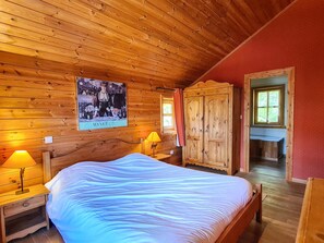 Camera da letto con pannelli in legno, un letto, comodini, un armadio e un poster appeso al muro.