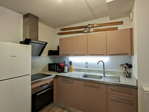 A kitchen with a Bosch refrigerator, a microwave, an oven, a sink, and wooden skis mounted on the wall.