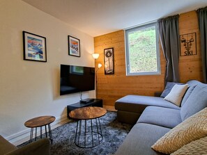 A modern living room with a flat-screen TV, a sofa, a coffee table, and a lamp.