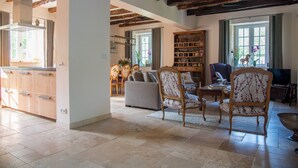 A spacious living area with a fireplace, wooden beams, a bookshelf, and a dining area. - HOUSE OF CEDAR, BEAUTIFUL STONE HOUSE IN DORDOGNE. (Auriac-du-Périgord)