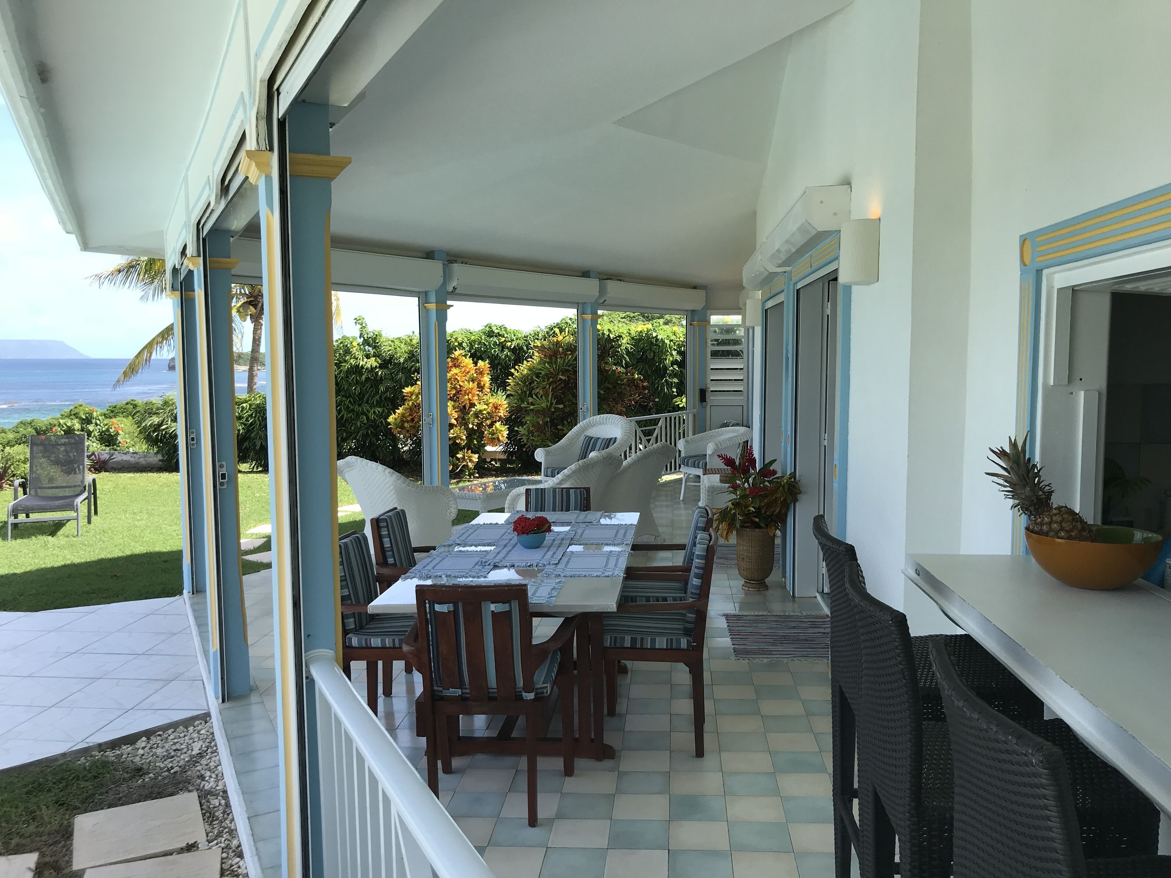 A covered patio with a dining table, chairs, and a grill.