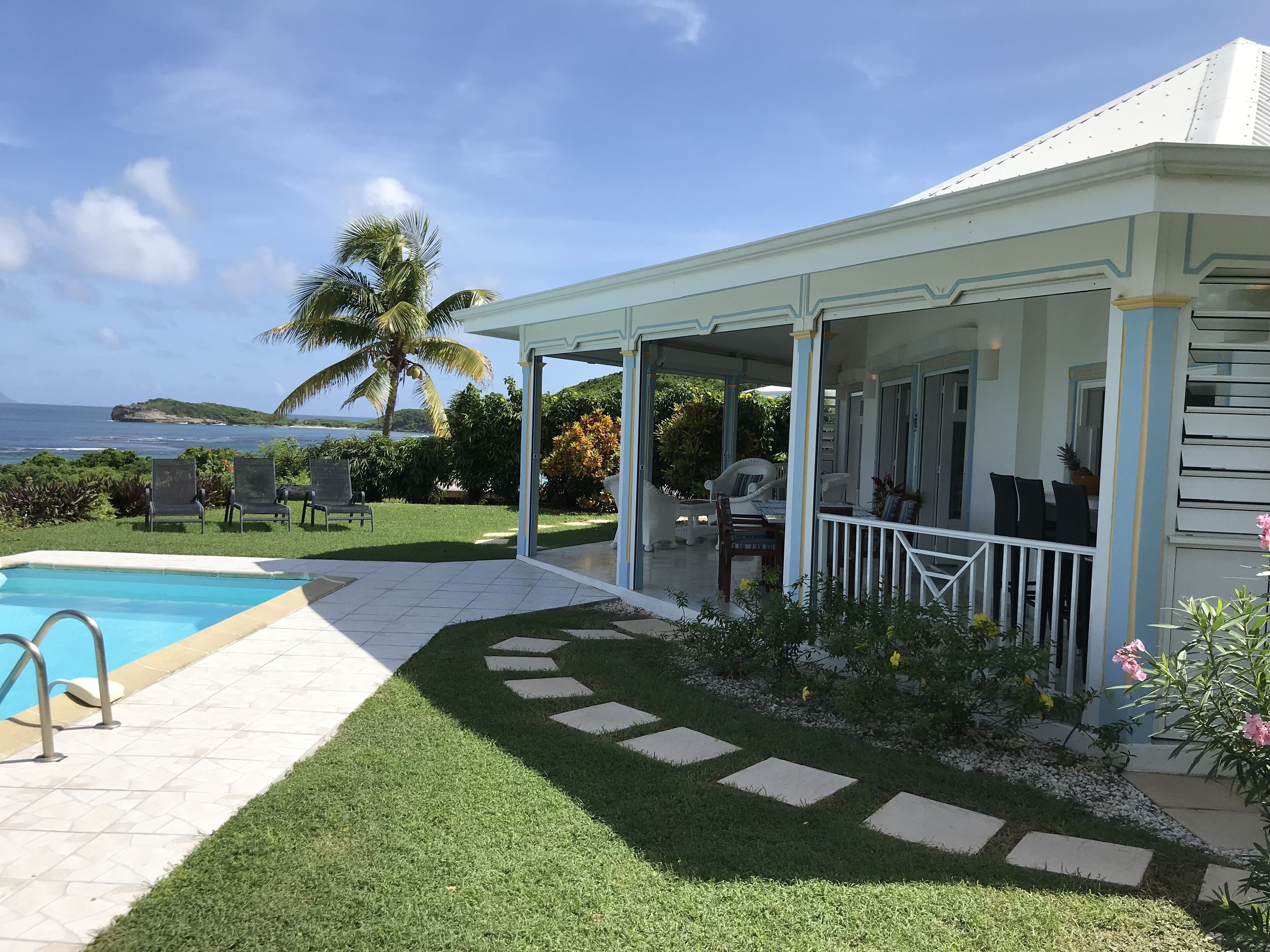 Ein überdachter Außenbereich mit Pool, Sitzgelegenheiten und Meerblick.